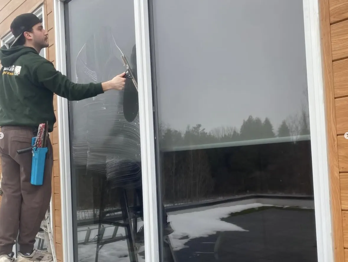 Doering Window Cleaning technician using squeegee on large sliding glass doors in Guelph Ontario